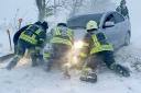 Ukrainian emergency workers try to push a car trapped in snow on the Odesa region highway (Ukrainian Emergency Service via AP Photo)